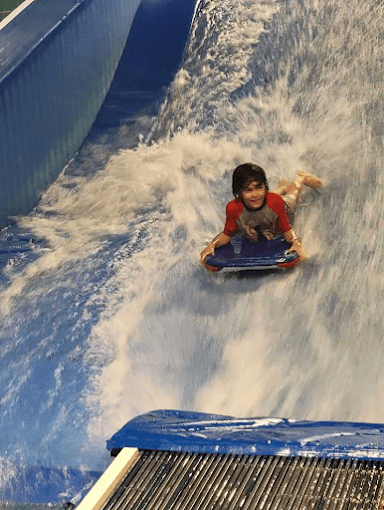 Kid on boogie board riding Flow Rider